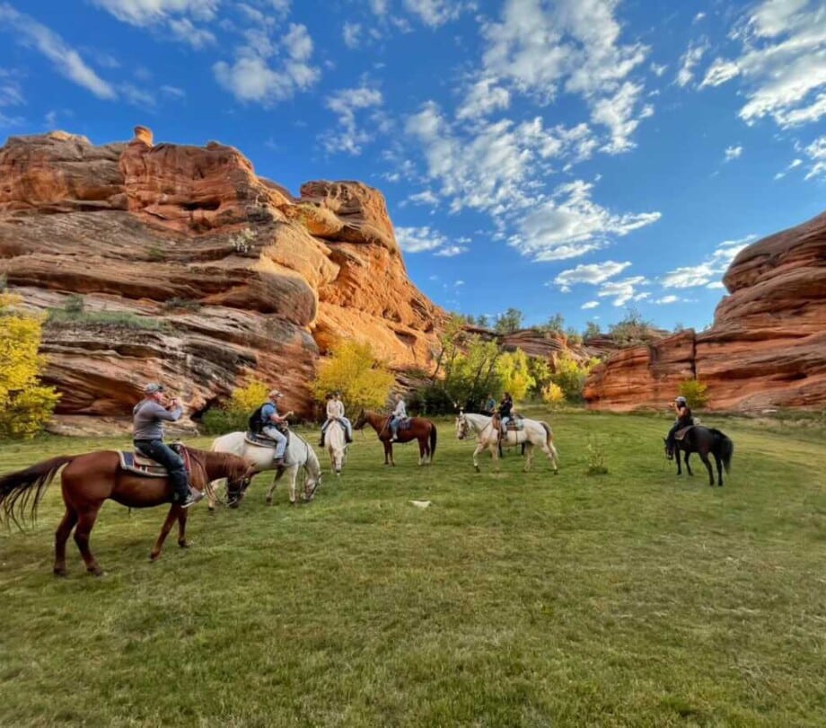 Horseback riders in a valley near a canyon.