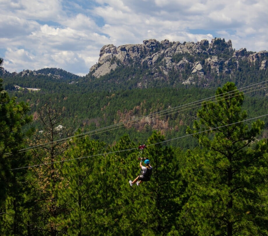 Person on a zipline with Mount Rushmore in the background.